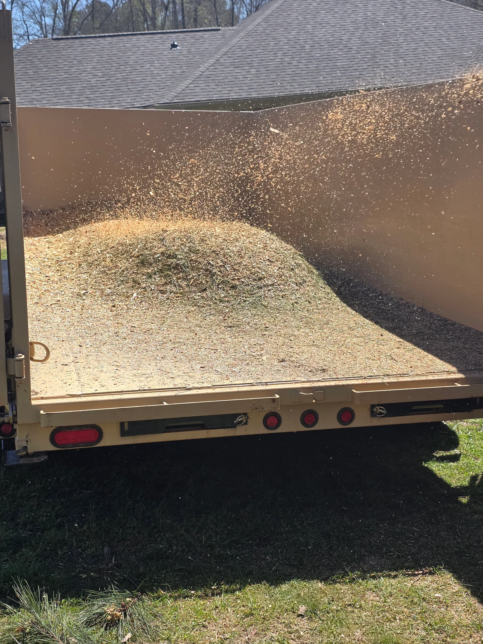 Dump trailer loaded with wood chips, branches, and mixed debris material