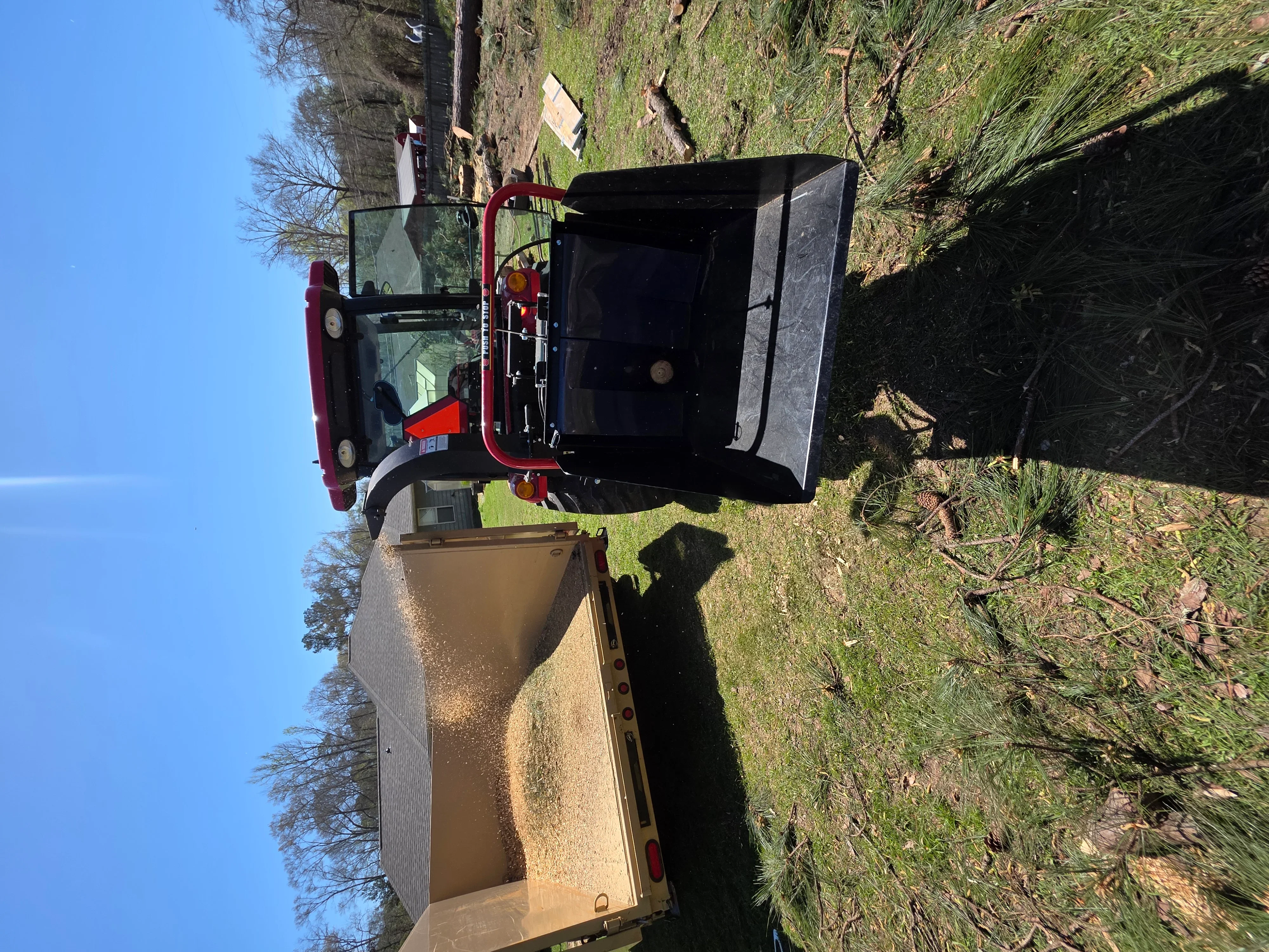 Red dump truck with open bed and hydraulic lift gate loaded with construction debris