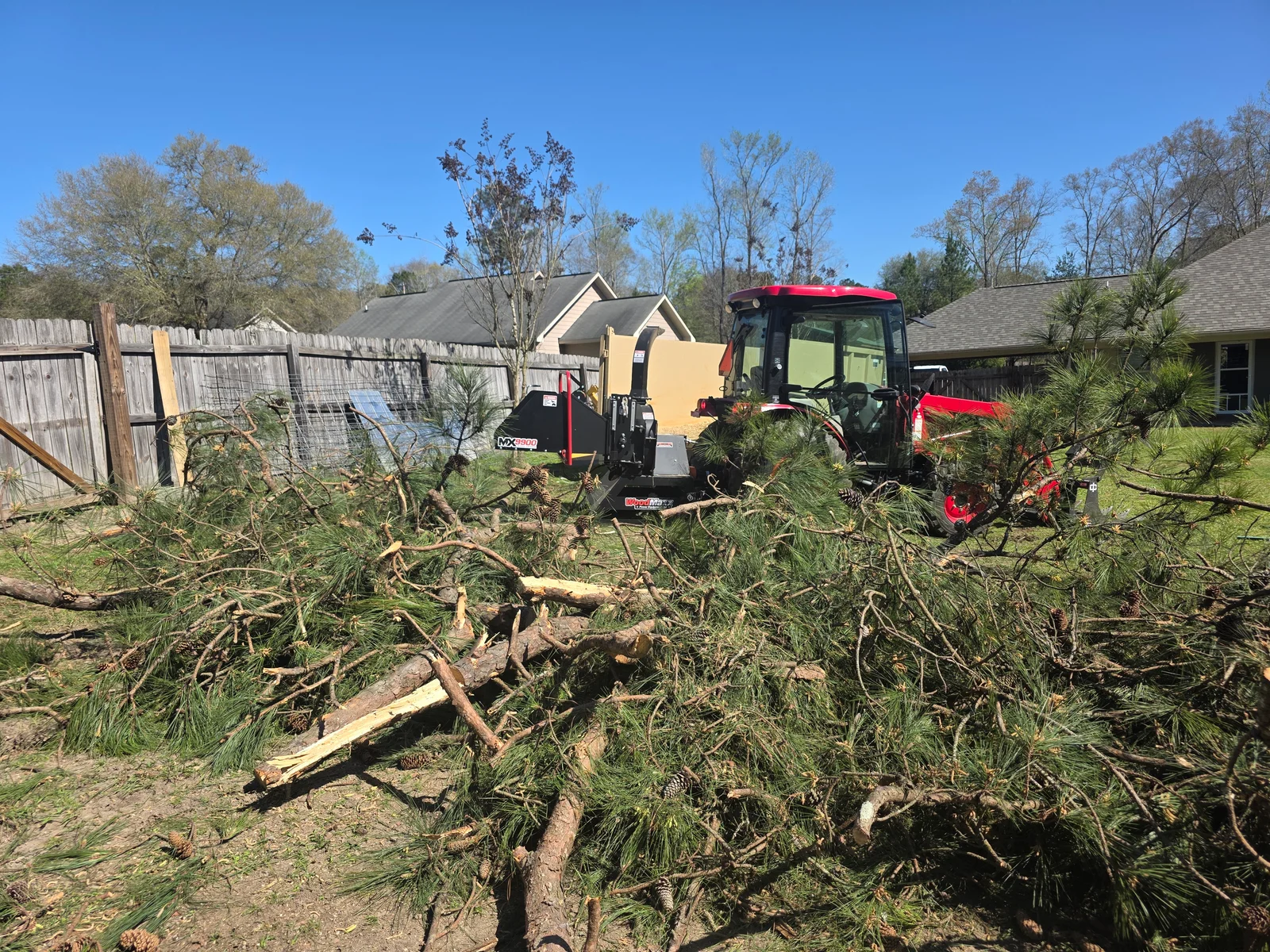 Debris removal equipment processing fallen trees and branches on residential lot