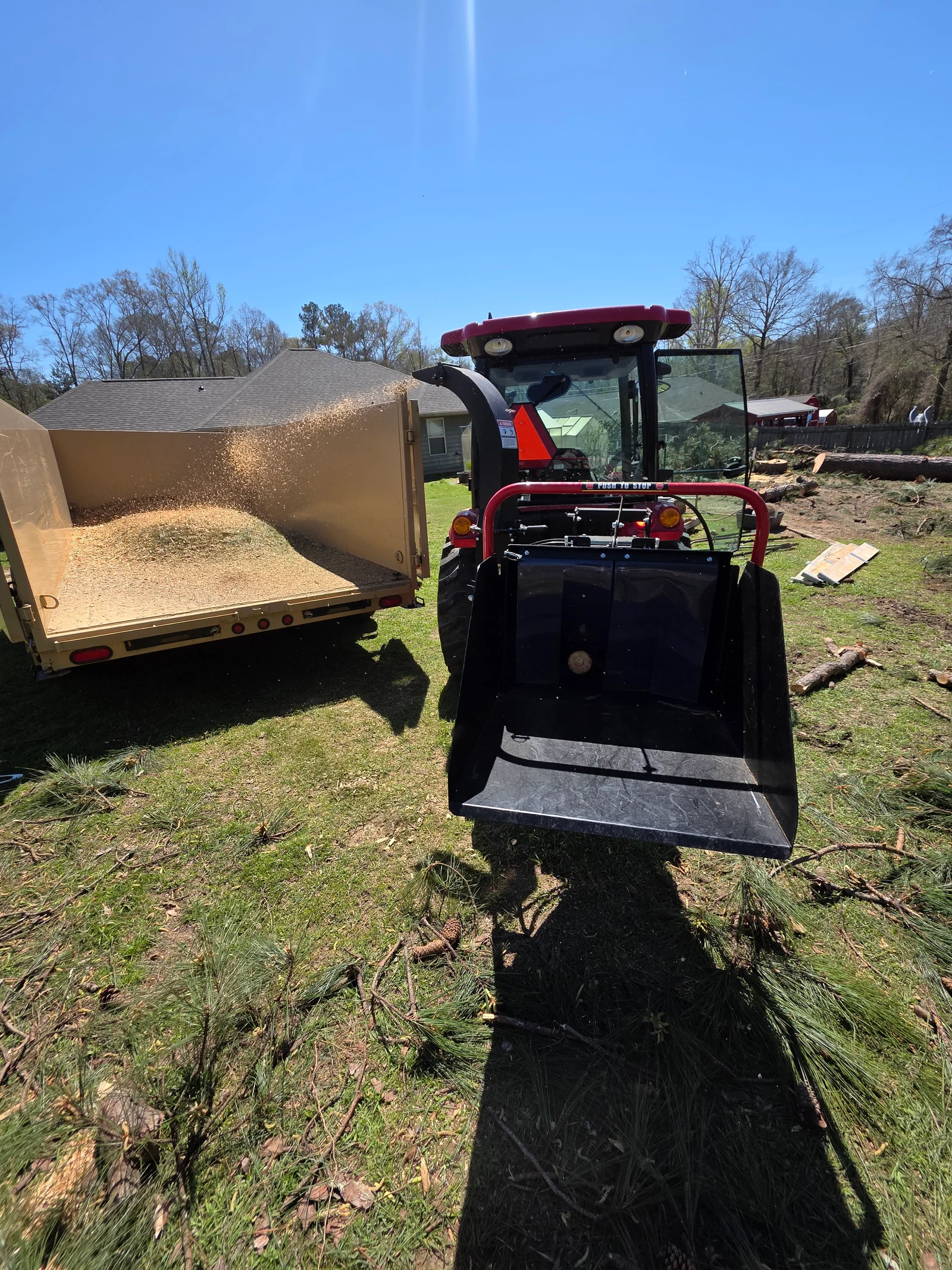 Compact track loader with bucket loading debris into enclosed trailer on residential property