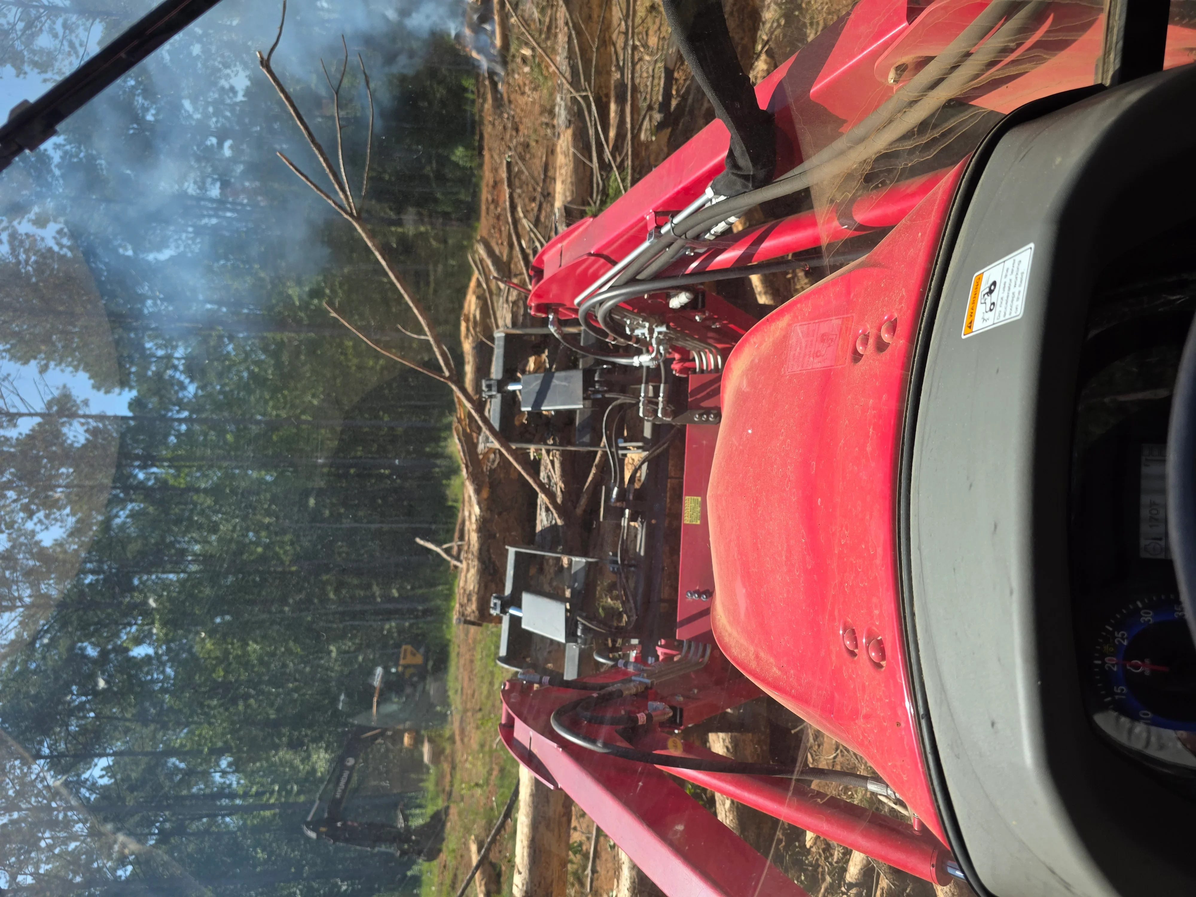 Red wood chipper and equipment removing large dead tree from wooded property