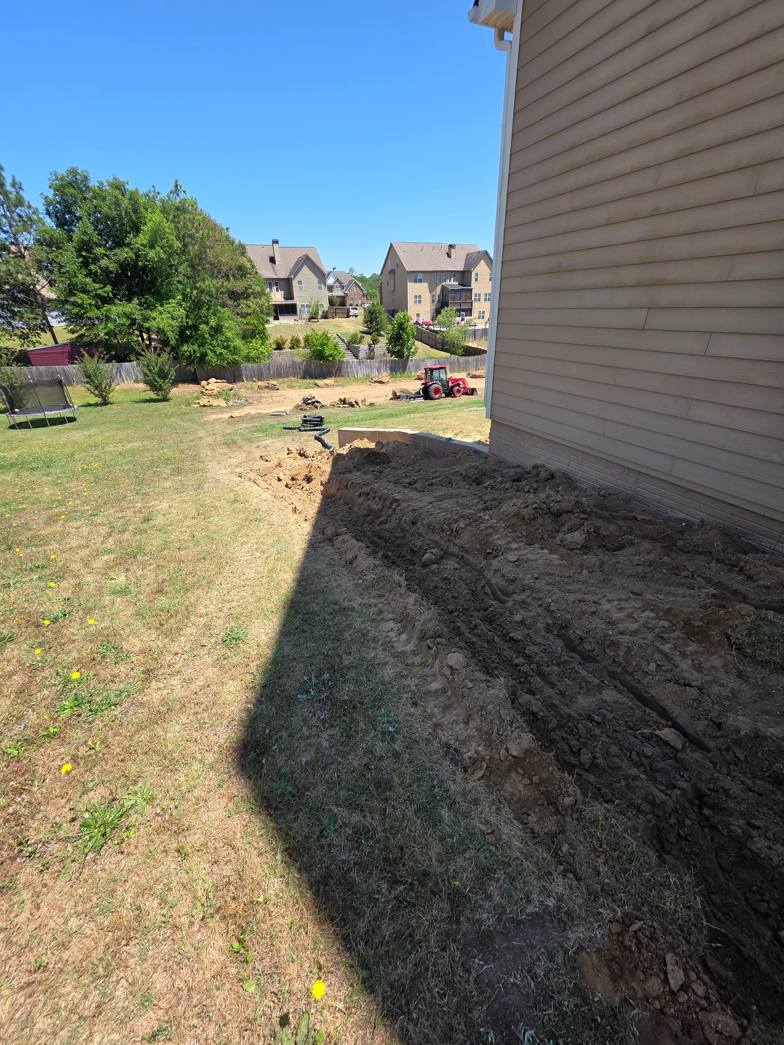 Excavated backyard lot with soil pile and cleared residential property ready for grading