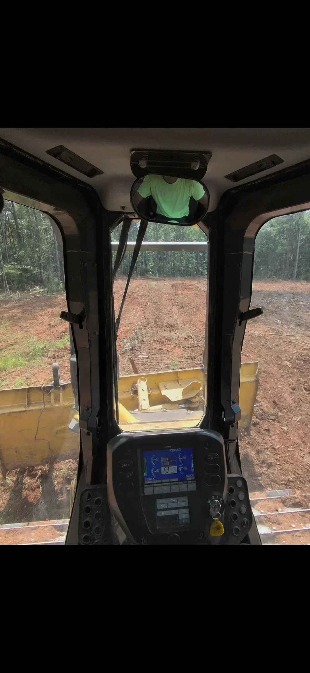 A tracked machine reshaping and leveling a raw dirt lot in Columbus, GA, with soil moved into sloped contours to direct drainage away from a future building pad. The surrounding terrain shows the clay-heavy soil typical of the Chattahoochee Valley region.